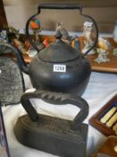 A large old cast iron kettle and a flat iron.