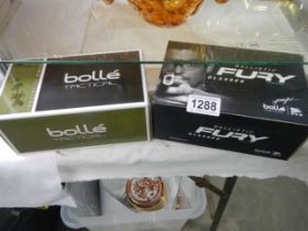 A boxed pair of Ballistic Fury glasses and a boxed pair of Bolle' tactical glasses.