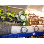 A wicker basket with faux flowers, magazine rack and owl draught excluder