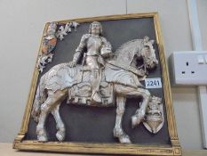 A wall plaque featuring a knight on horse back.