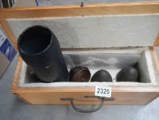 A wooden box containing a gun shell and three shell heads.