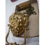A brass lion head door knocker and other brassware.