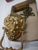 A brass lion head door knocker and other brassware.