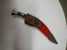 A vintage kukri with stone encrusted gilded red velvet scabbard.