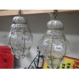 A pair of wire bound blown glass lanterns, approximately 40 cm drop.