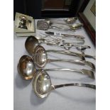 Four silver plate soup ladles and other cutlery.