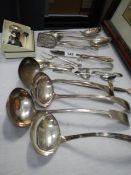 Four silver plate soup ladles and other cutlery.