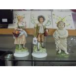 A pair of continental bisque figures and another of a toddler with dog.