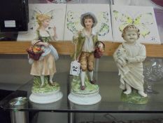 A pair of continental bisque figures and another of a toddler with dog.