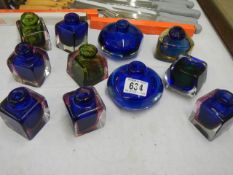 A quantity of coloured glass inkwells.