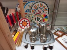 A colourful lot of table mats/coasters plus stainless steel tea set on tray, candlesticks, candles