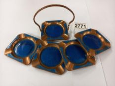 A copper and enamel ashtray stand with four ashtrays.