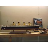 A plastic scale model of the Titanic length 77cm approx and a book and wooden rowing boat COLLECT