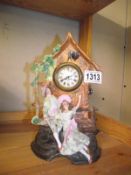 A bisque mantel clock depicting Courting Couple on bench with clock housed in a roofed folly COLLECT