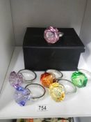 A set of six coloured glass and metal napkin rings in the style of a solitaire ring.