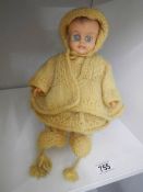 A vintage doll in hand knitted clothing.