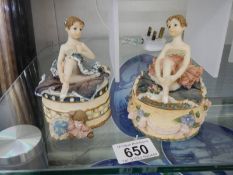 Two trinket boxes with ballerina's on top.