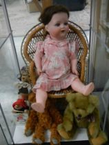A Vintage doll in a high chair and various teddy bears.