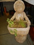 A composite stone garden statue of a boy carrying a planter. COLLECT ONLY.