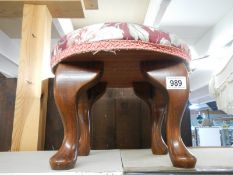 A circular footstool on Queen Anne style legs