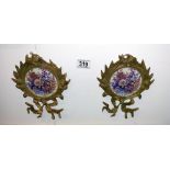 A pair of brass wall hangings with floral pottery inserts