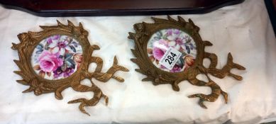 A pair of brass wall hangings with rose pattern plaques