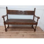 Early 20th C. carved oak hall bench with inset leather seat raised on turned legs in the Tudor style