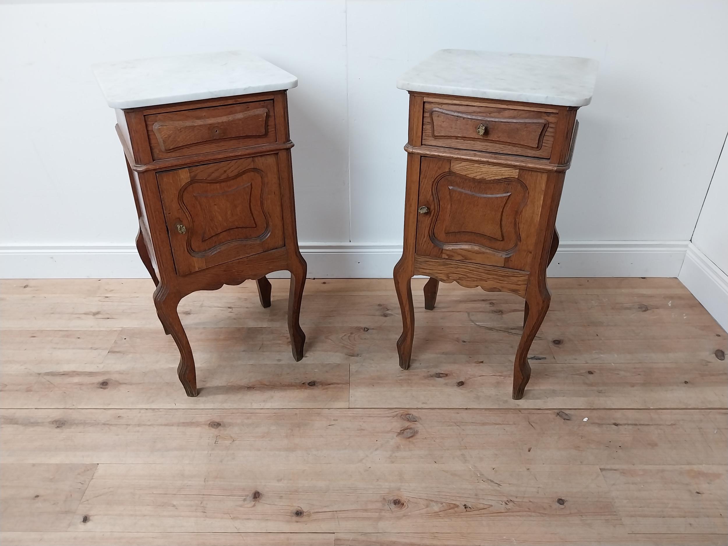Pair of early 20th C. oak bedside cabinets with marble tops and single drawer above panelled door