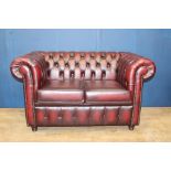 Deep buttoned red leather two seaeter Chesterfield soda raised on bun feet {H 84cm x W 150cm x D