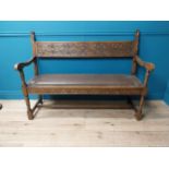 Early 20th C. carved oak hall bench with inset leather seat raised on turned legs in the Tudor style