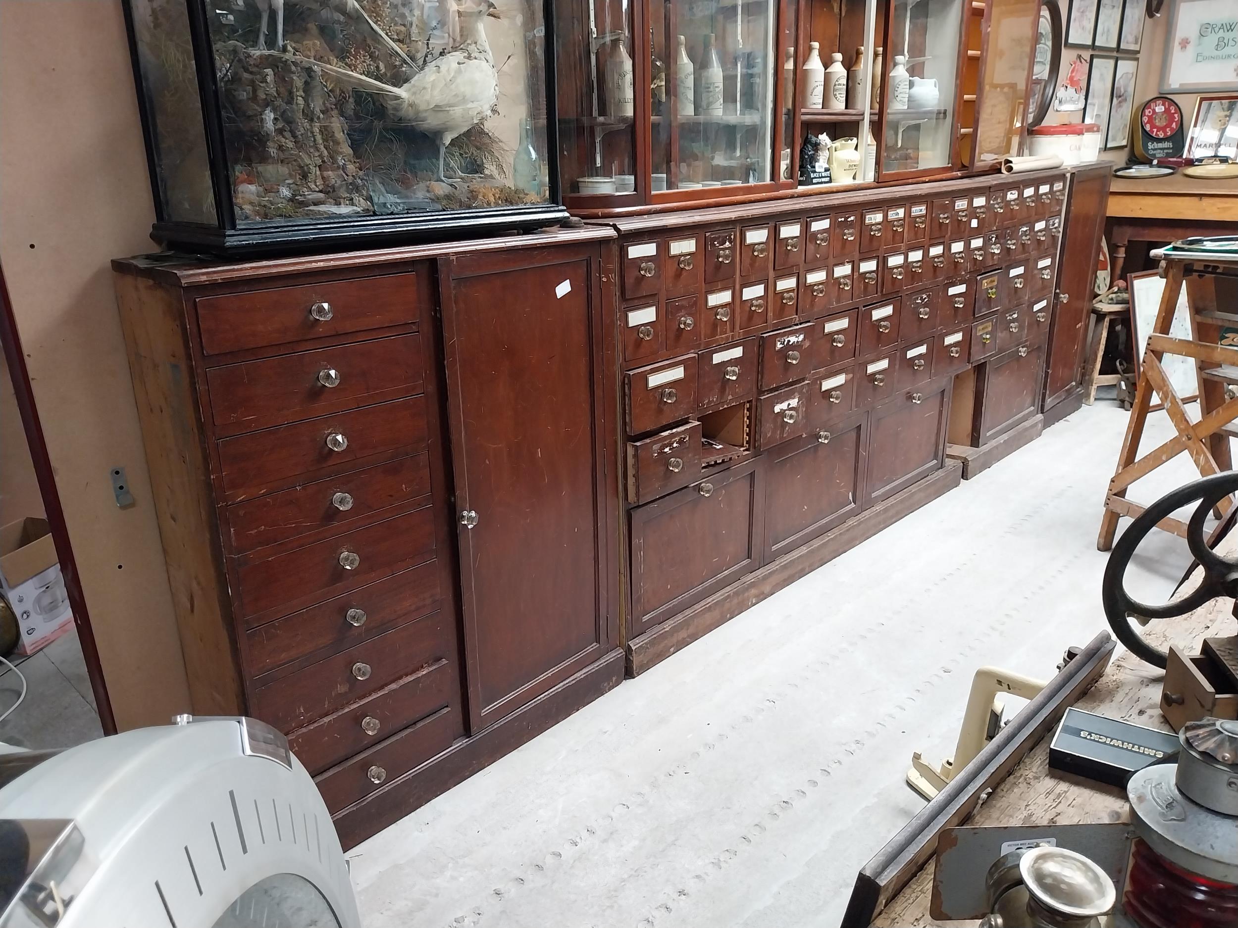 Early 20th C mahogany bank of sixty chemist drawers with original glass handles flanked by two