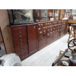 Early 20th C mahogany bank of sixty chemist drawers with original glass handles flanked by two