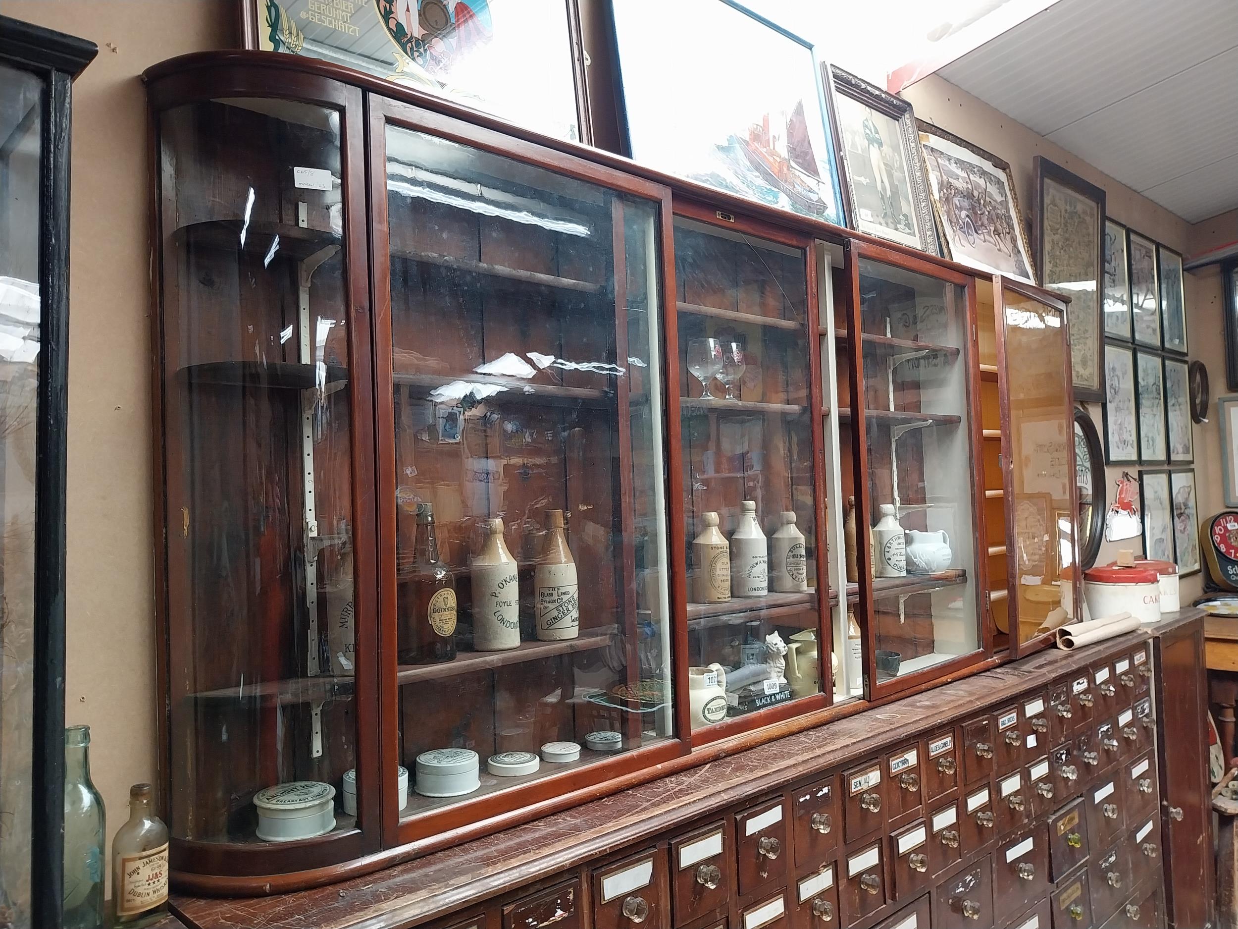 Early 20th C mahogany wall mounted glazed chemist cabinet {102cm H x 252cm W x 36cm D}