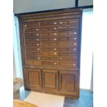 Early 20th C. oak office cabinet with bank of twenty seven drawers above three blind doors in need