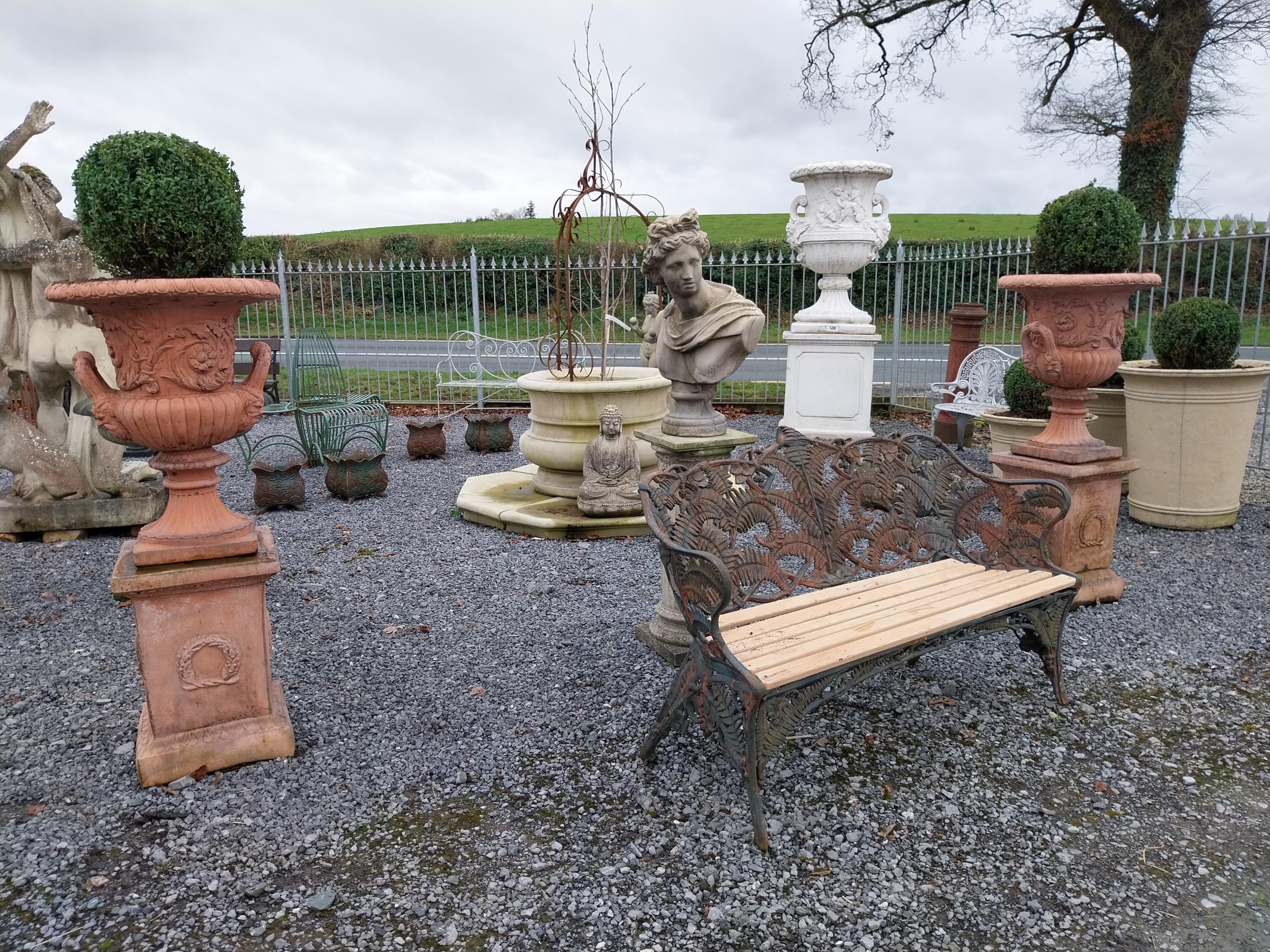 Pair of moulded stone terracotta urns with floral and lion's masks decoration on pedestal in the