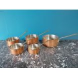 Set of five good quality graduated copper and brass saucepans with tin liners {19 cm H x 39 cm W x