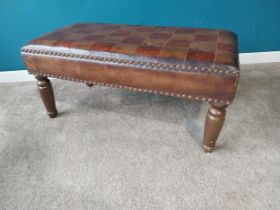 Leather upholstered footstool on turned stained pine legs. {47 cm H x 102 cm W x 52 cm D}.{ cm H