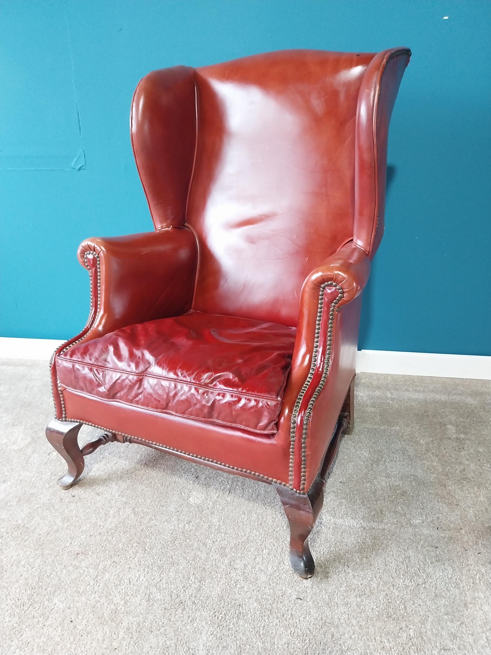 Leather wingback armchair raised on mahogany cabriole legs {114 cm H 77 cm W 67cm D}.