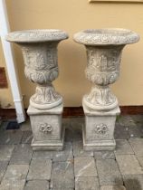 Pair of stone urns with leaf decoration on square pedestal bases. {96 cm H x 41 cm Dia.}.