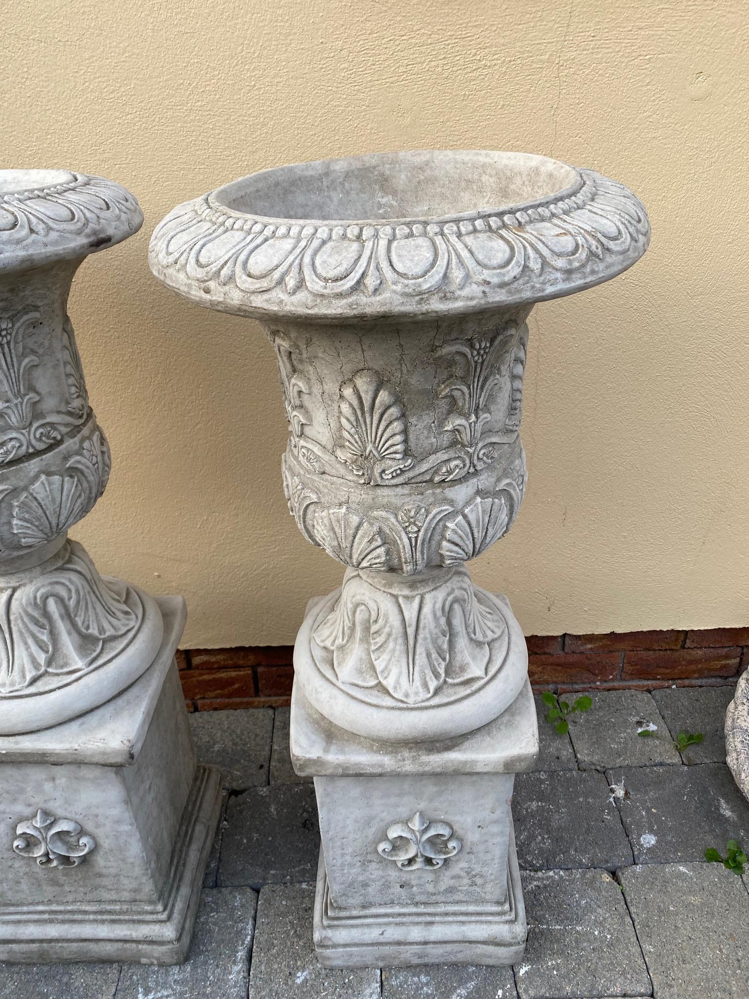 Pair of stone urns with leaf decoration on square pedestal bases. {96 cm H x 41 cm Dia.}. - Image 2 of 5