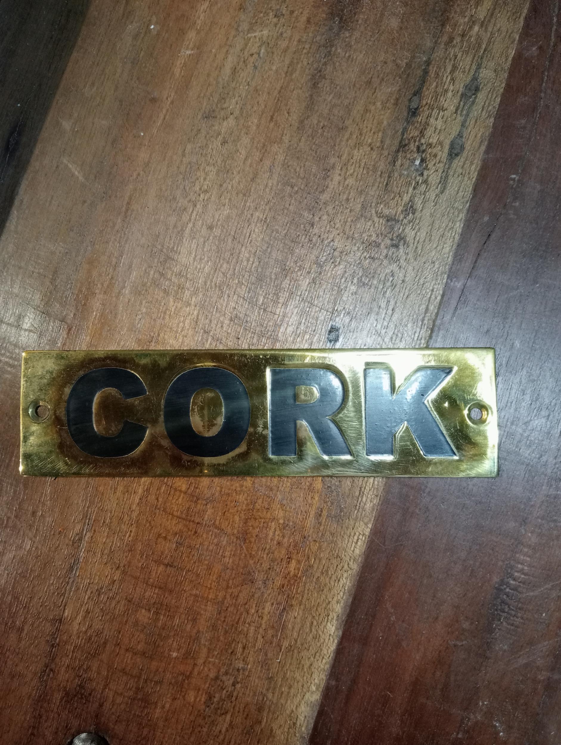 Cork brass wall sign {H 4cm x W 15cm }.