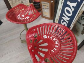 Two Farmall tractor seats on cast iron stands. {79 cm H x 41 cm W x 37 cm W}