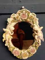 Capodimonte oval mirror decorated with cherubs and flowers. {H 45cm x W 31cm }.