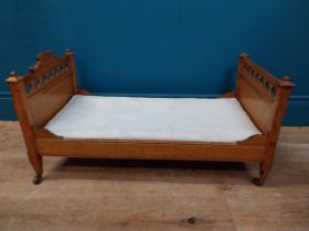 Early 20th C. oak dog bed with side panels decorated with cherubs on tapered feet and brass casters.