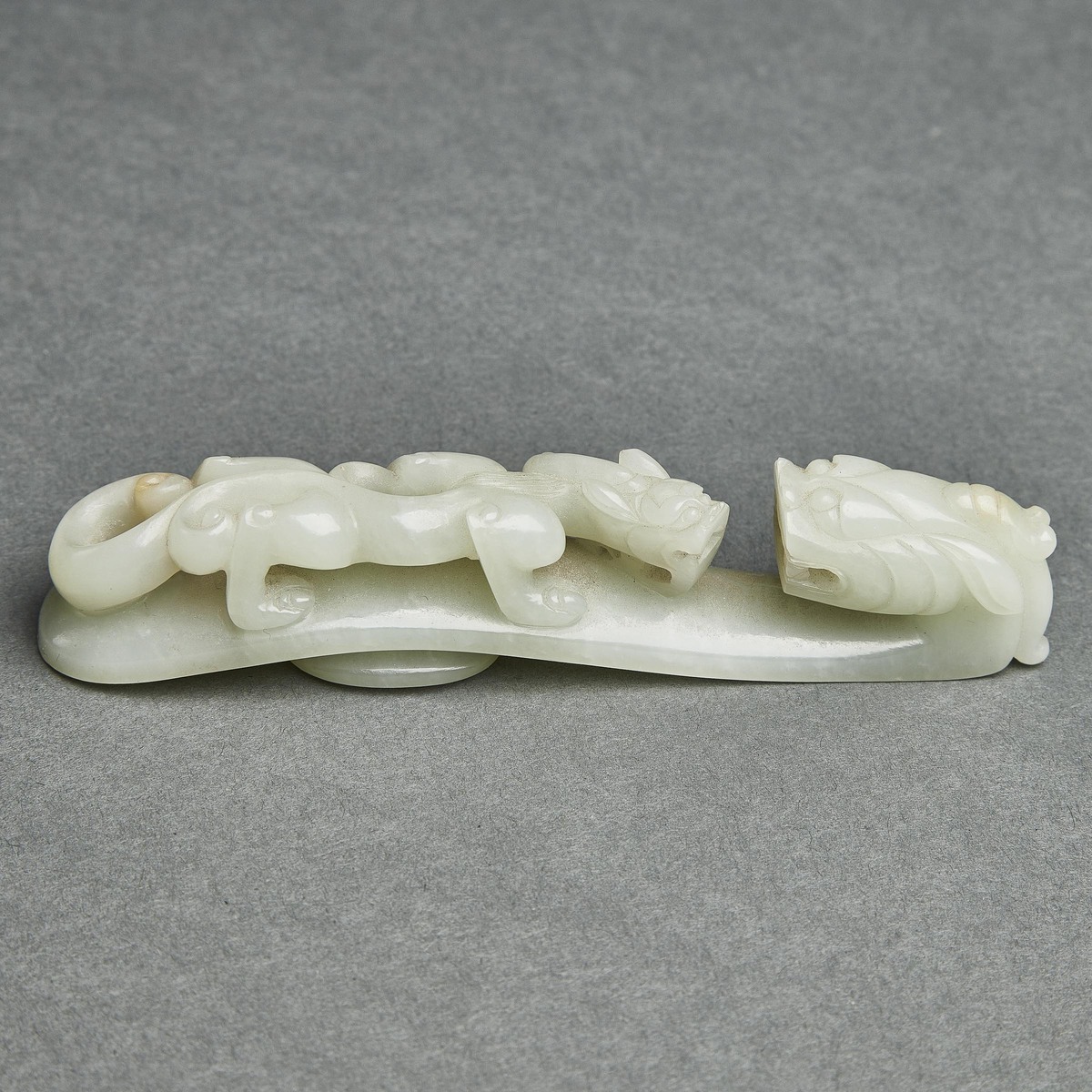 A Pale Celadon Jade 'Dragon' Belt Hook, Qing Dynasty, 清 青白玉雕'苍龙教子'带扣, length 5 in — 12.8 cm