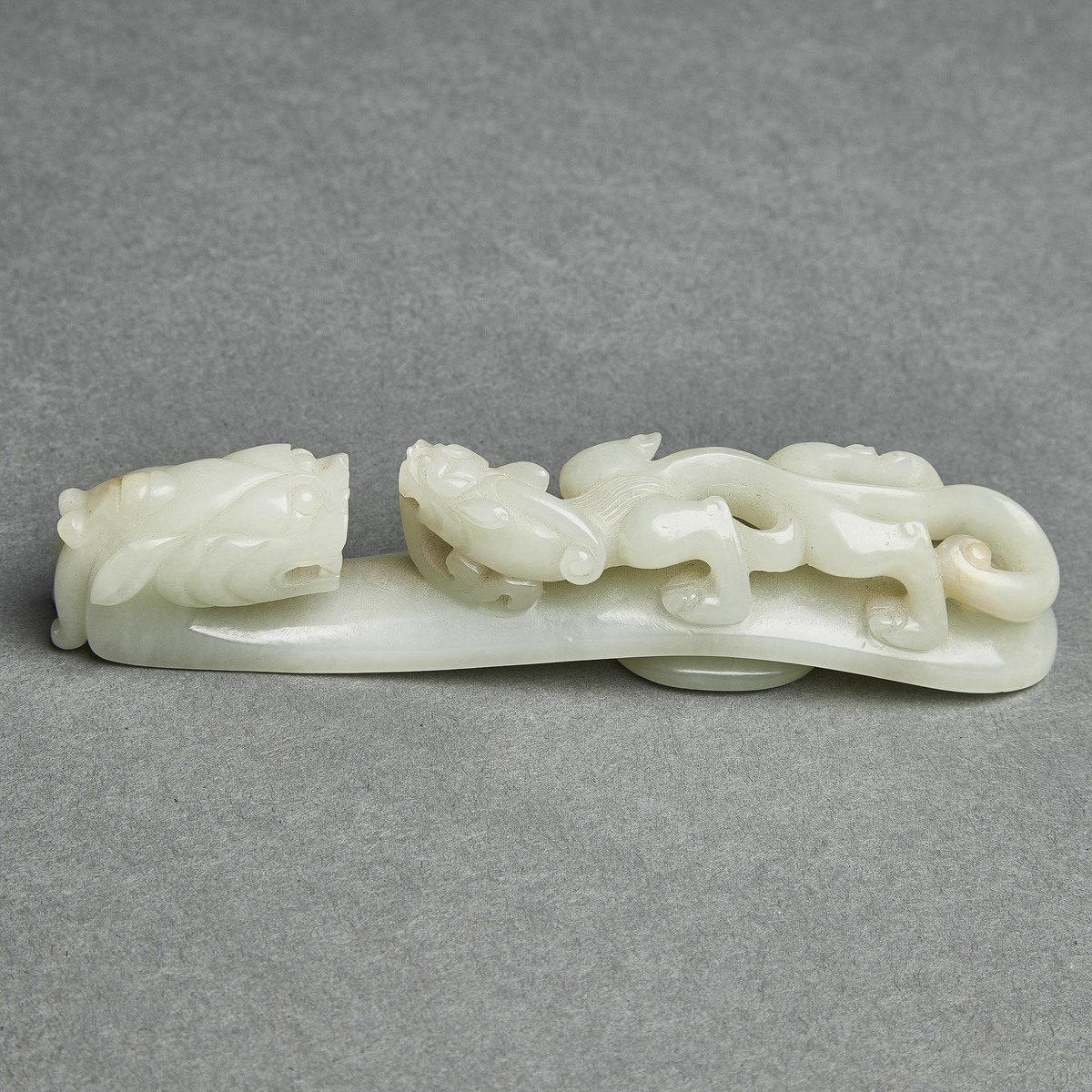 A Pale Celadon Jade 'Dragon' Belt Hook, Qing Dynasty, 清 青白玉雕'苍龙教子'带扣, length 5 in — 12.8 cm - Image 2 of 8