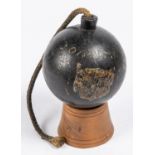 A large iron explosive cannon ball, bearing traces of painted armorial shield and inscribed "