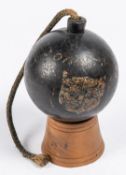 A large iron explosive cannon ball, bearing traces of painted armorial shield and inscribed "