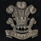 A white metal cap badge of the 1st Volunteer Battalion the Welsh Regiment, with blades. GC (
