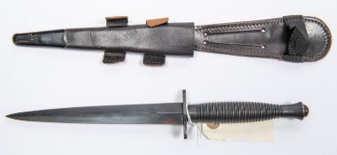 A Third pattern FS fighting knife, blued blade 6¾", ribbed blackened hilt, in its leather sheath.